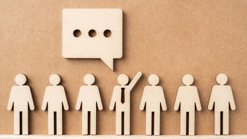 a group of wooden people standing in front of a speech bubble