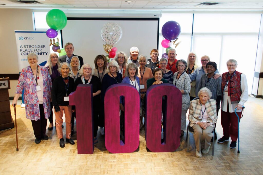 Group of members posing behind large "100" letters at CHF BC's centennial celebration