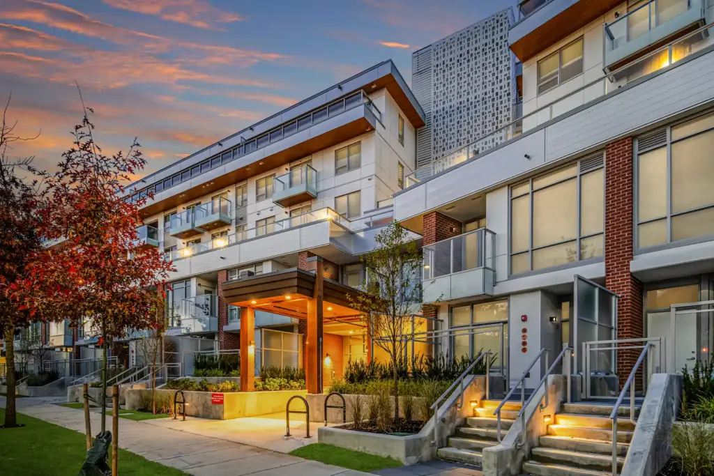 Modern low-rise apartment building at dusk with a lit entrance