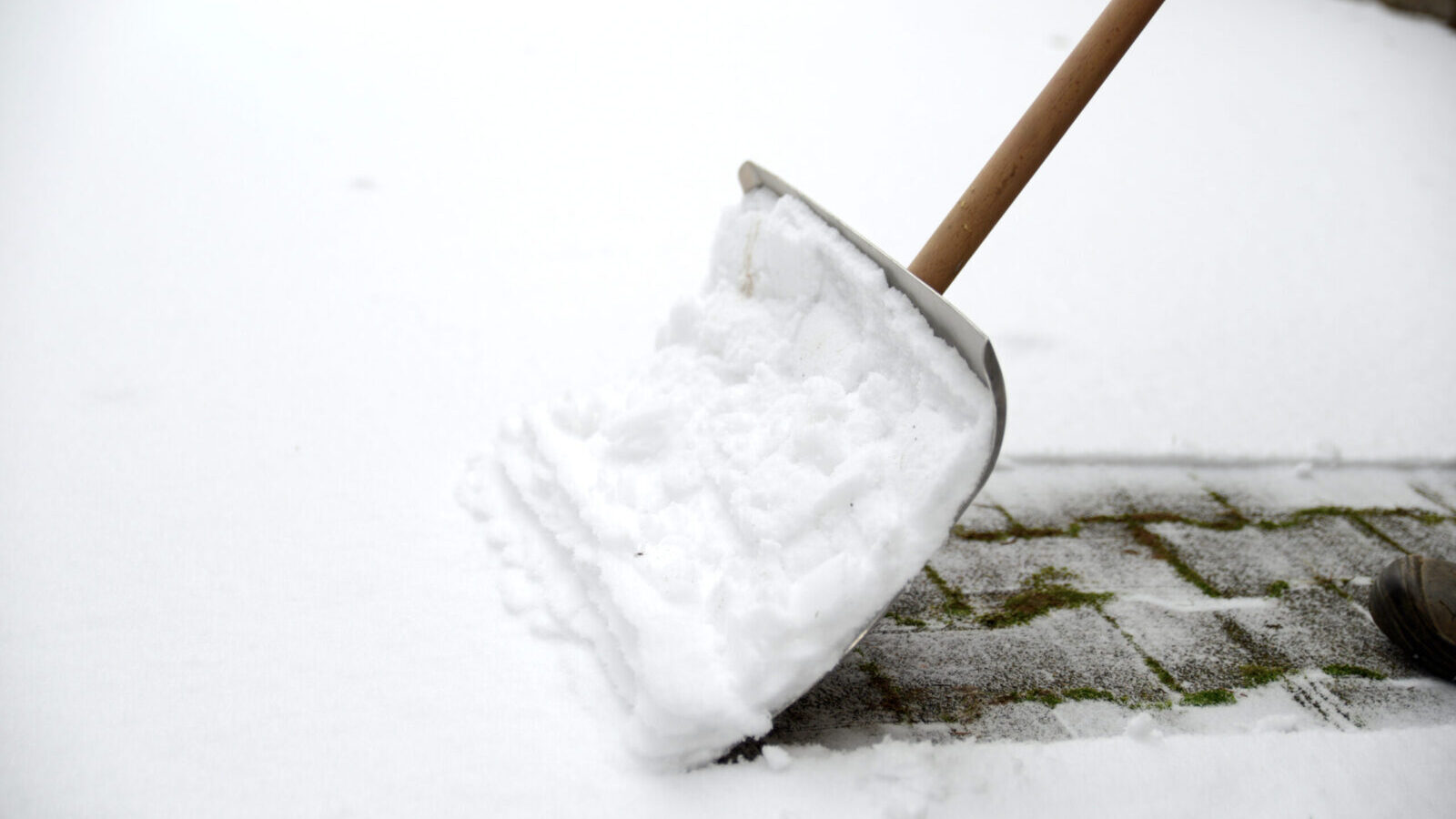 Snow shovel clearing snow from a paving-stone walkway