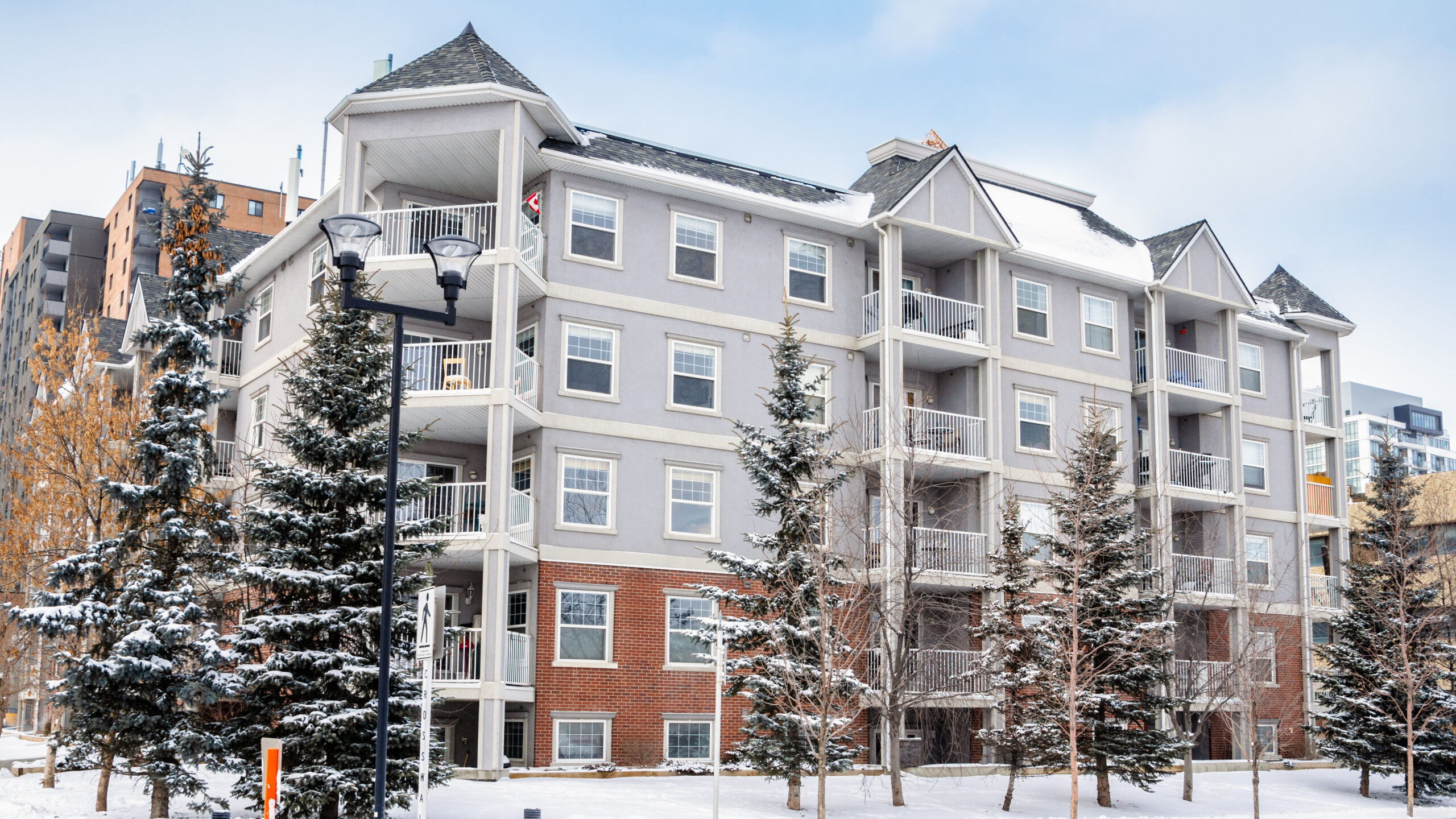 Exterior of a modern apartment building in winter with snow-covered evergreens