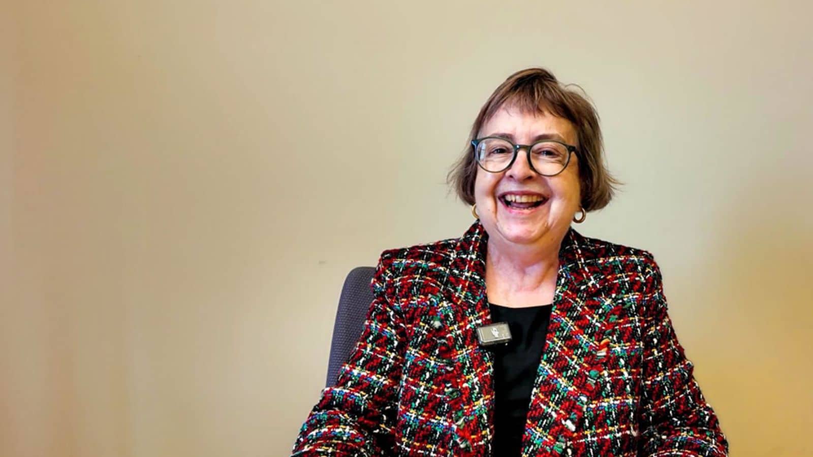 Smiling woman in a tweed blazer and glasses