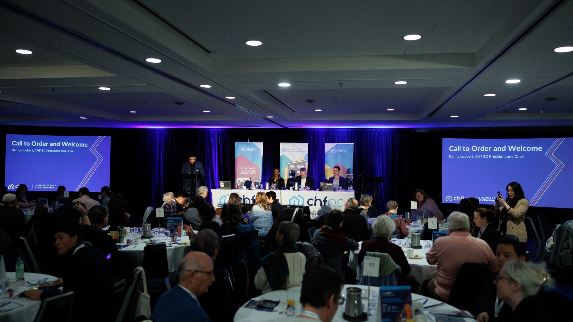 Attendees seated at tables during a CHF BC forum's call to order