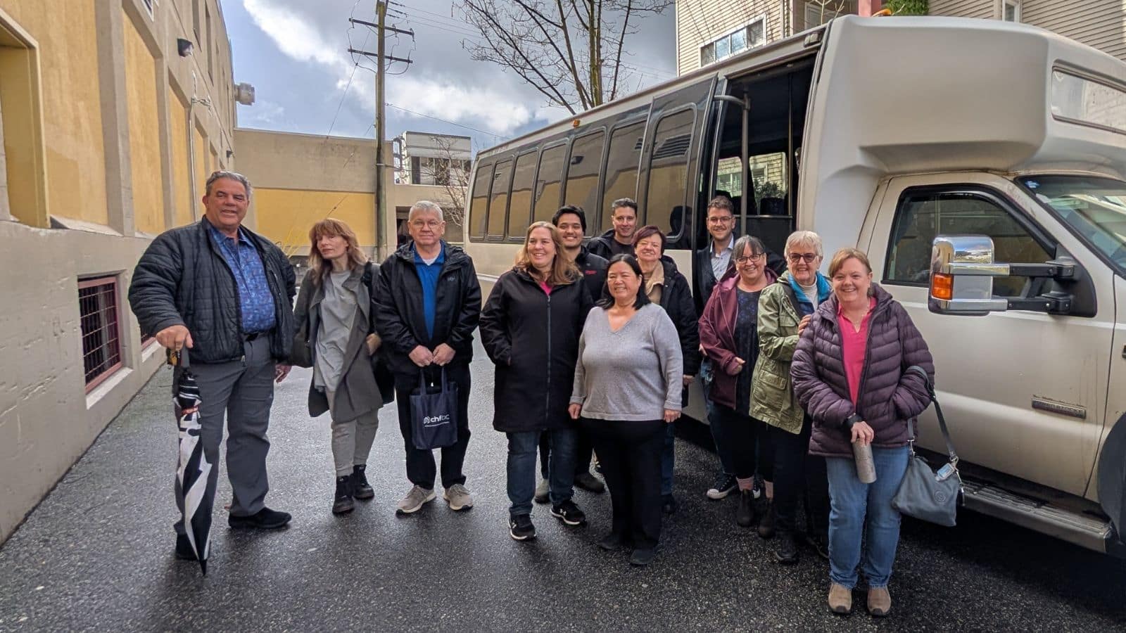 Group gathered beside a bus for a Community Land Trust tour