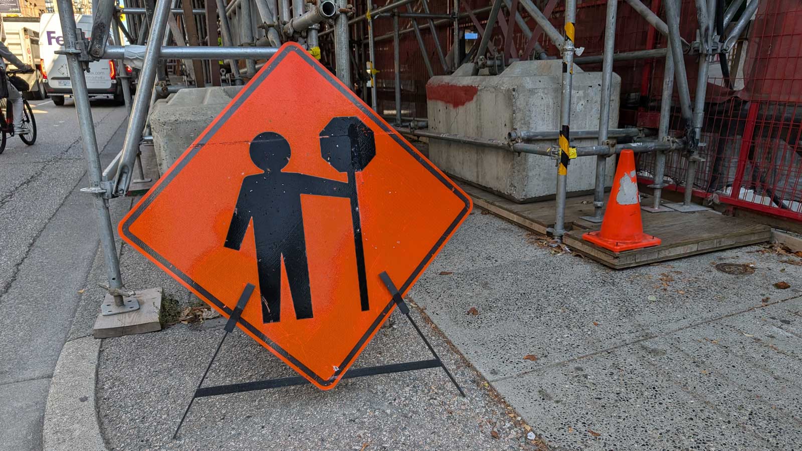 Construction worker warning sign on a downtown sidewalk beside scaffolding