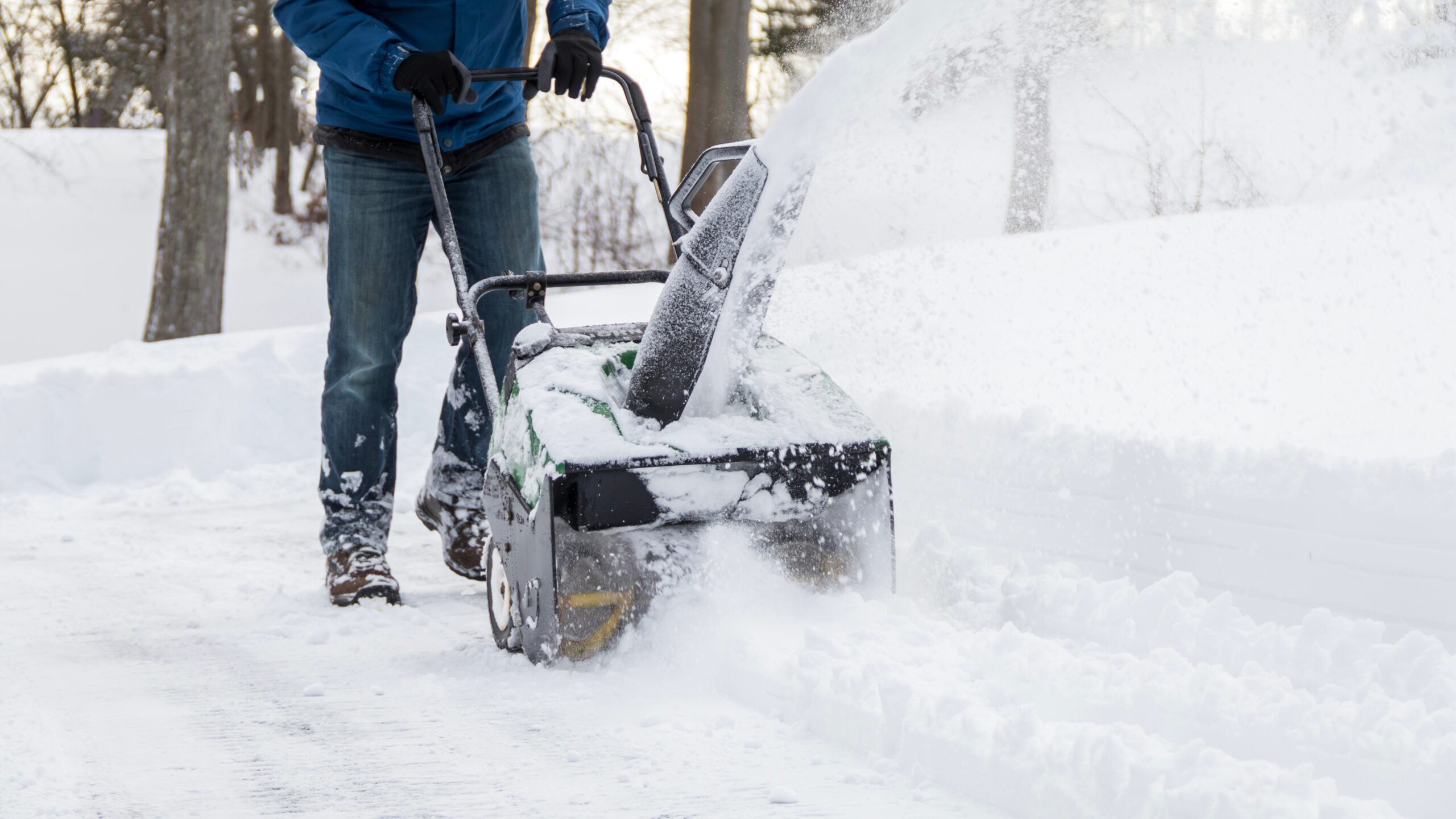 Person clearing snow from a driveway with a snow blower